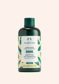 A bottle of The Body Shop Banana Truly Nourishing Conditioner with a green label, featuring an image of a banana and leaves.