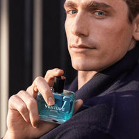 Man holding a blue 'Venture' perfume bottle with a dark background